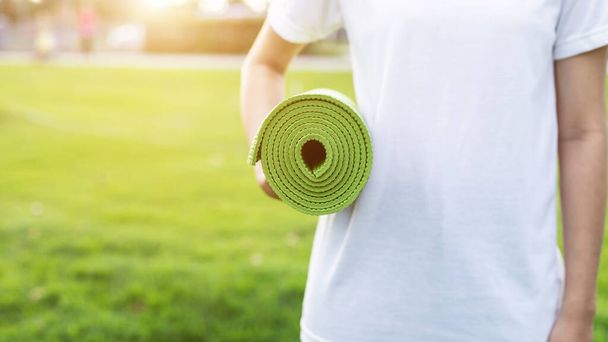 Pretty asian holding green yoga mat and prepare for doing yoga e - Foto, afbeelding