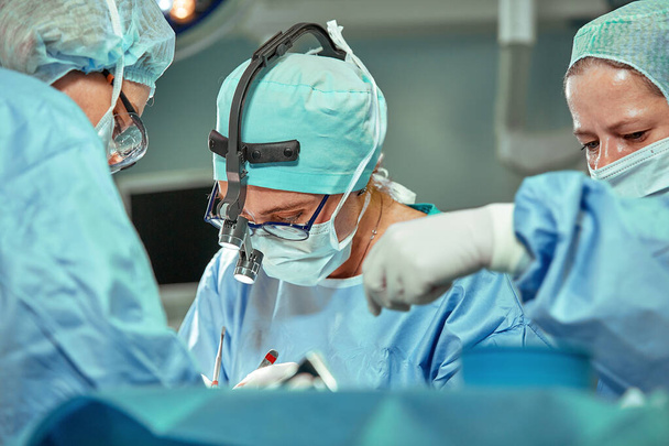 Grupa lekarzy, patrząc na pacjenta na stole operacji podczas ich pracy - Zdjęcie, obraz