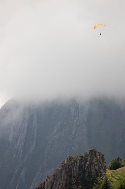 Mann mit Gleitschirm fliegt in den Bergen - Foto, Bild