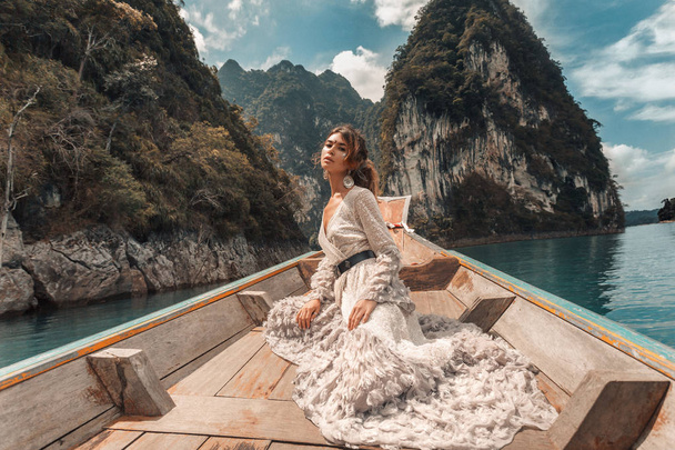 fashionable young model in elegant dress on boat at the lake  - Photo, image