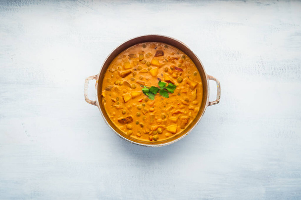 Indisches Essen: Currytopf voller Erbsen und Kartoffeln mit dekorativem Koriander - Foto, Bild