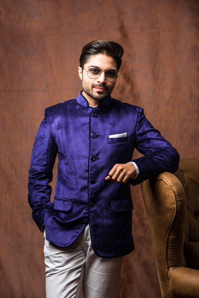 Indian Man porte des tissus ethniques ou traditionnels, modèle de mode avec manteau violet et pantalon blanc, posant sur fond brun grunge, mise au point sélective
 - Photo, image