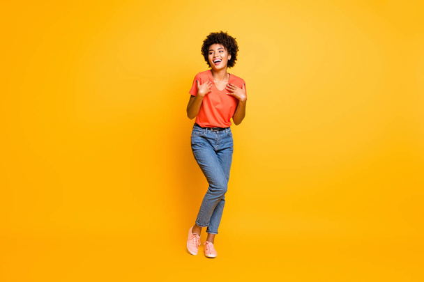 Full length body size photo of cheerful curly wavy black lady wearing jeans denim unable to believe in being chosen excited rejoicing isolated over yellow vivid color background - Foto, imagen