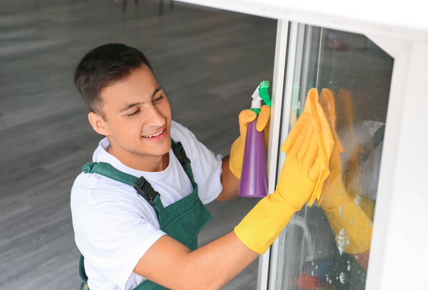 Fiatal férfi takarít ablakot otthon - Fotó, kép