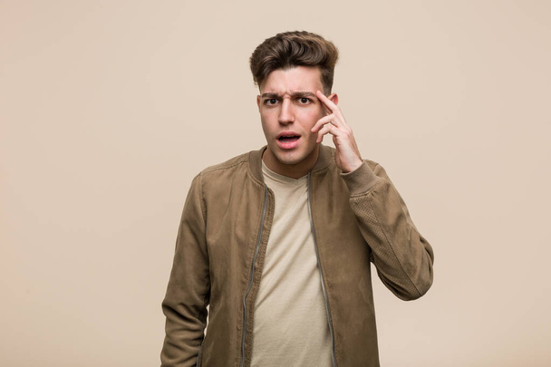 Young caucasian man wearing a brown jacket showing a disappointment gesture with forefinger. - Photo, image