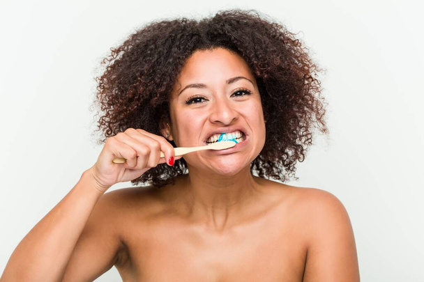 Κοντά σε μια νεαρή αφρικανική Αμερικανίδα που βουρτσίζει τα δόντια της με μια οδοντόβουρτσα - Φωτογραφία, εικόνα