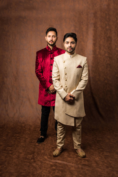 dva indičtí muži nosí etnické nebo tradiční oblečení, pánské módní modely s sherwani nebo Kurta Pyjama, stojící a pózující na hnědém pozadí grunge, selektivní zaměření - Fotografie, Obrázek