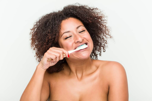 Κοντά σε μια νεαρή αφρικανική Αμερικανίδα που βουρτσίζει τα δόντια της με μια οδοντόβουρτσα - Φωτογραφία, εικόνα