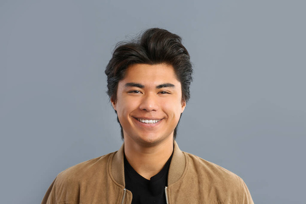 Portrait of handsome Asian man on grey background - Photo, Image
