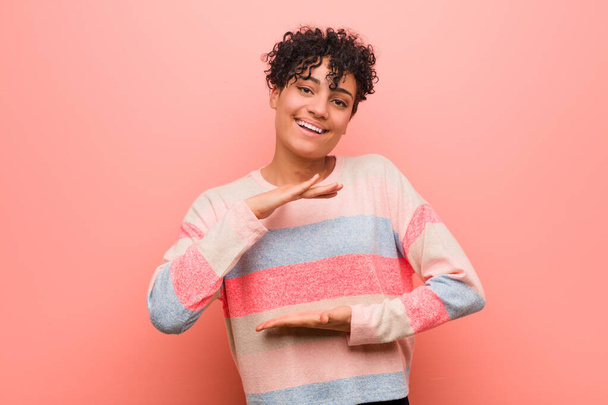 Jeune femme adolescente afro-américaine mixte tenant quelque chose avec les deux mains, présentation du produit
. - Photo, image