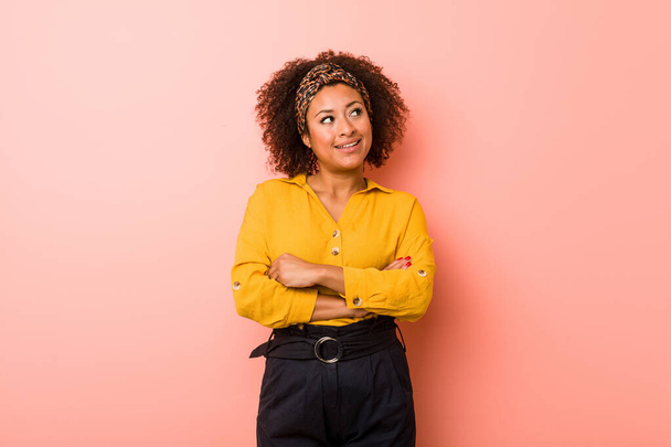 Young african american woman against a pink background smiling confident with crossed arms. - Foto, Imagen