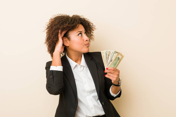 Mladá africká americká žena drží dolary a snaží se poslouchat klepy. - Fotografie, Obrázek