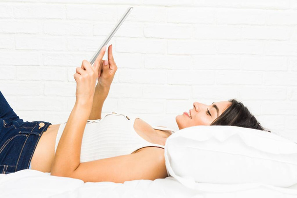 Fiatal Arab nő feküdt az ágyon használ tabletta - Fotó, kép