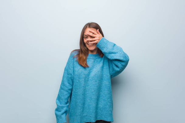Jeune jolie femme portant un pull bleu embarrassé et riant en même temps
 - Photo, image