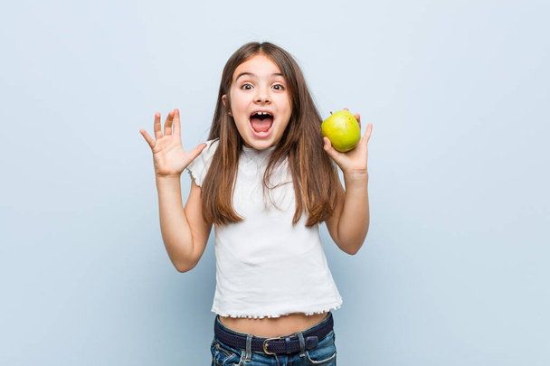 Little kaukaskie dziewczyna gospodarstwa zielone jabłko świętuje zwycięstwo lub sukces - Zdjęcie, obraz