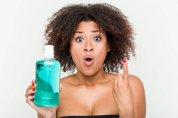 Young african american woman holding mouthwash having some great idea, concept of creativity. - Photo, Image