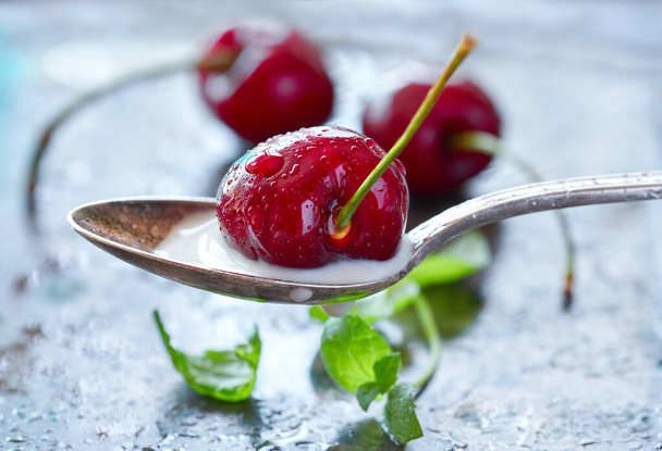Close-up on a spoon with cream and dark cherry with more cherrie - Foto, immagini