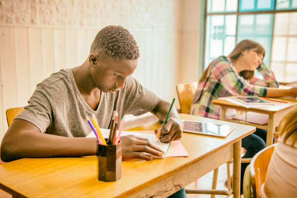 Afrikaanse jongen in het klaslokaal doet schooltest. - Foto, afbeelding