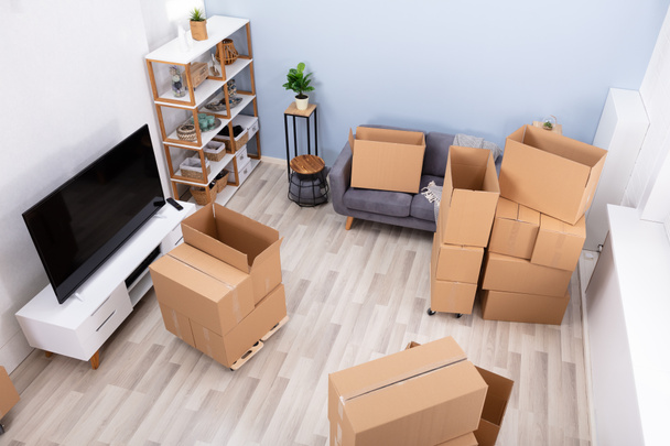 Stack Of Brown Moving Cardboard Boxes Are On Hardwood Floor In Living Room - Zdjęcie, obraz