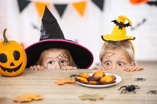 Young two girls in halloween costumes looking on the cookies - Photo, image