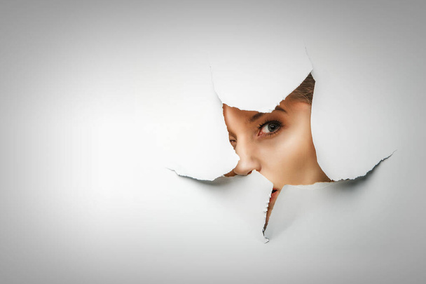 Woman looking out from a hole of torn paper - Fotografie, Obrázek
