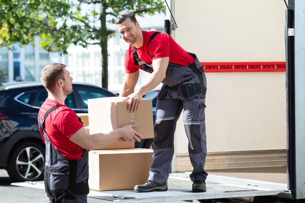 Deux jeunes déménageurs masculins en uniforme portant des boîtes en carton de camion
 - Photo, image