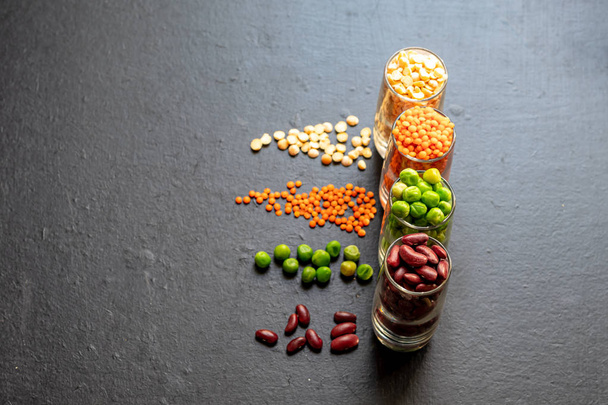 A selection of bean products for vegetarian dishes and more. Beans, peas, fresh and dried, lentils. They are rich in protein and useful elements. Copy space. Dark background. - Foto, Imagem