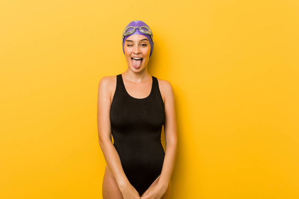 Young swimmer caucasian woman funny and friendly sticking out tongue. - Foto, Bild