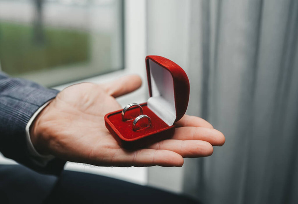 Stříbrné snubní prsteny na dlani ženicha v svatební den.  - Fotografie, Obrázek