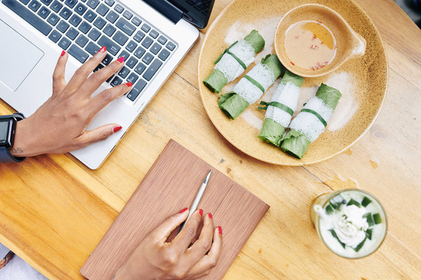 Gros plan d'une femme d'affaires tapant sur un ordinateur portable et dînant à une table en bois
 - Photo, image