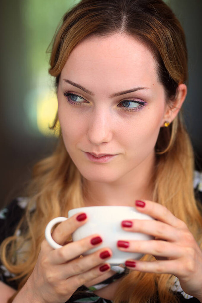 pensive and smiling woman with a cup of coffee - Fotografie, Obrázek