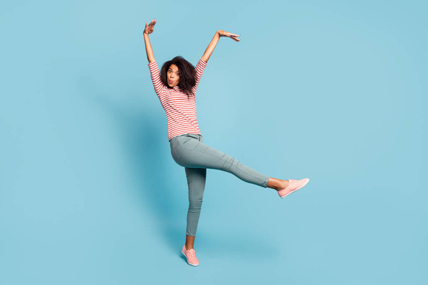 Full length photo of funny dark skin wavy lady making crazy facial expressions raising hands up foolish mood wear casual clothes isolated pastel blue color background - Valokuva, kuva