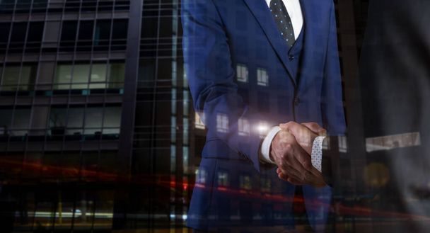 夜のライトで握手するビジネスマン背景 - 写真・画像