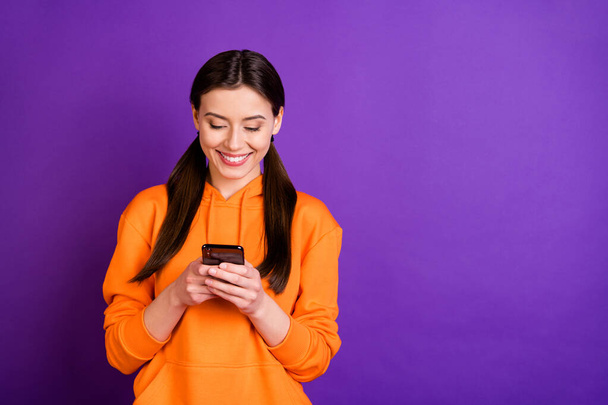 Portrait of positive cheerful youngster use her cellphone follow blogs bloggers wear sporty wear hood isolated over violet purple color background - Foto, Bild