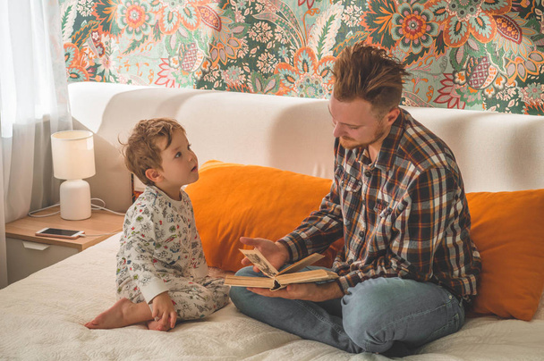 Papà e Figlio leggono un libro insieme, sorridendo e abbracciandosi. Felice giorno dei padri
. - Foto, immagini