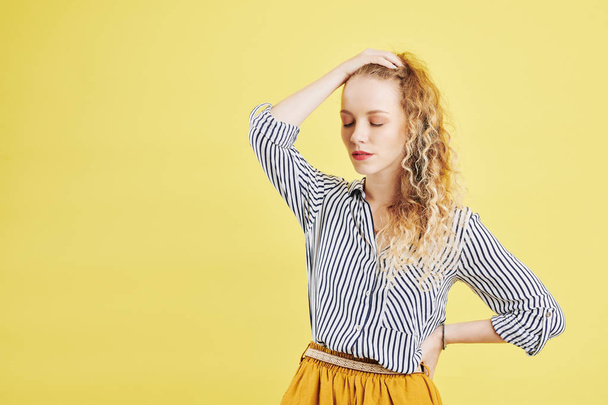 Beautiful stressed and tired young woman and touching her head, isolated on yellow  - Photo, Image