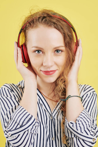 Retrato de una joven muy sonriente en blusa a rayas disfrutando escuchando podcast en auriculares
 - Foto, Imagen
