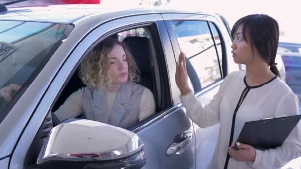 Авто бізнес, азіатська жінка продавець автомобілів консультуватися з клієнтом дівчиною в машині і руками через ключі після успішного продажу в шоу-румі
 - Кадри, відео