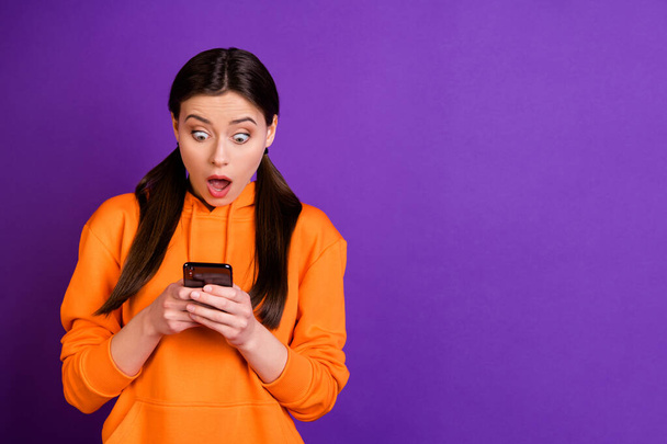 Portrait of impressed funky youngster girl use her smartphone get like dislike in her social networking account wear sporty wear isolated over violet purple color background - Φωτογραφία, εικόνα