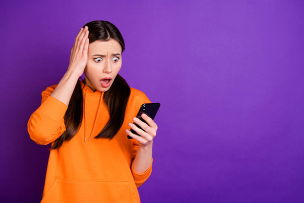 Portrait of astonished youth girl use her cellphone read feednews comment on social network accounts shout wow omg wear sporty wear isolated over violet purple color background - Foto, immagini
