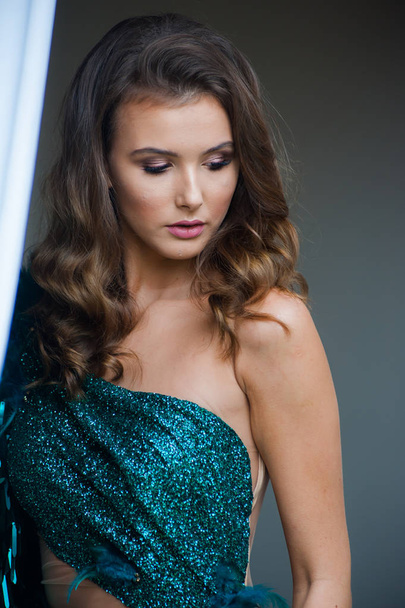 Fashionable emerald evening dress on a young woman with beautiful hair and makeup - 写真・画像