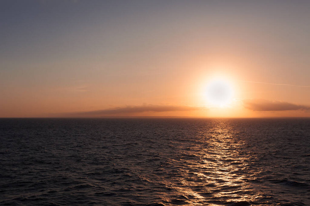 Sol prestes a pôr-se atrás do horizonte no mar com fundo litoral italiano
 - Foto, Imagem