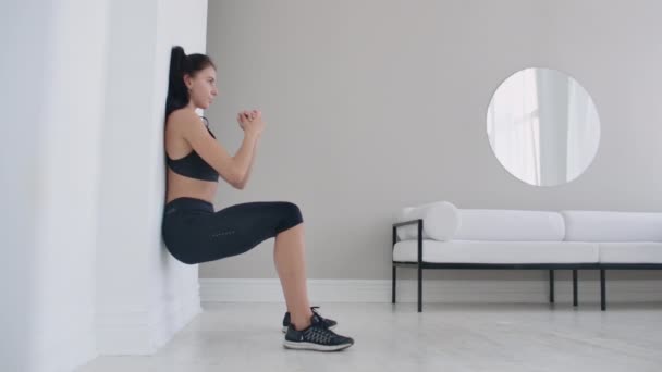 La fille brune gelée dans un squat appuyé sur le mur faisant un exercice statique
 - Séquence, vidéo