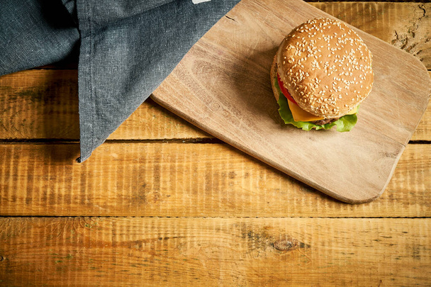 Top view of classic burger on wooden board and black background - Photo, Image