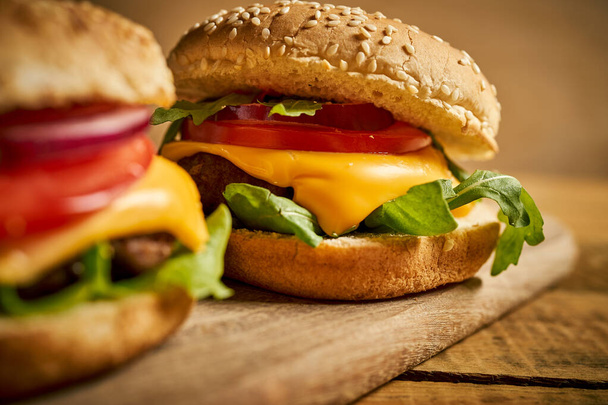Lezzetli hamburgerleri ahşap masa ve siyah arka planda yakın plan - Fotoğraf, Görsel