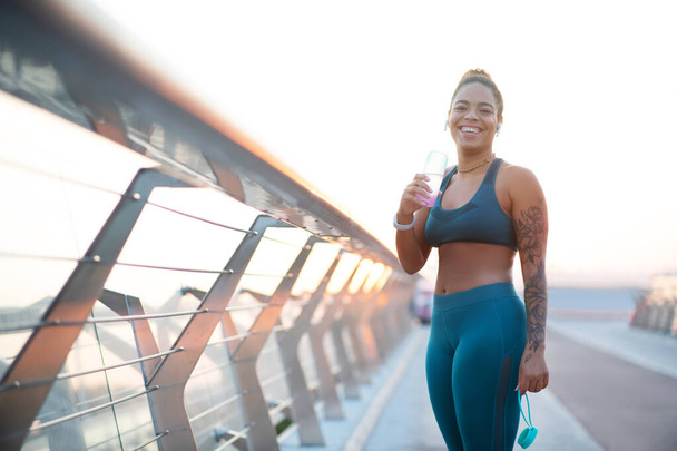 Woman laughing after running in the morning while drinking water - Foto, Bild