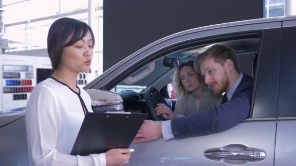 portrét prodavačky s klientem rodinného páru, který zobrazuje klíče uvnitř auta při nákupu auta v prodejním centru - Záběry, video