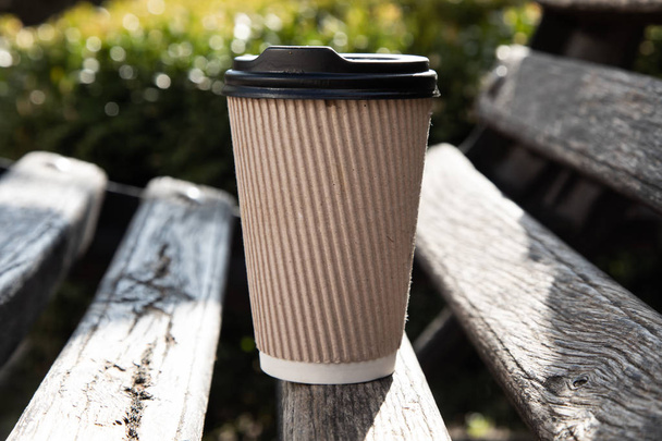 Una taza de café de papel con tapa en un banco
 - Foto, Imagen