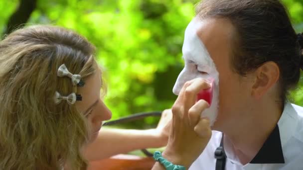 Dívka malovat tvář mladému muži mime s - Záběry, video
