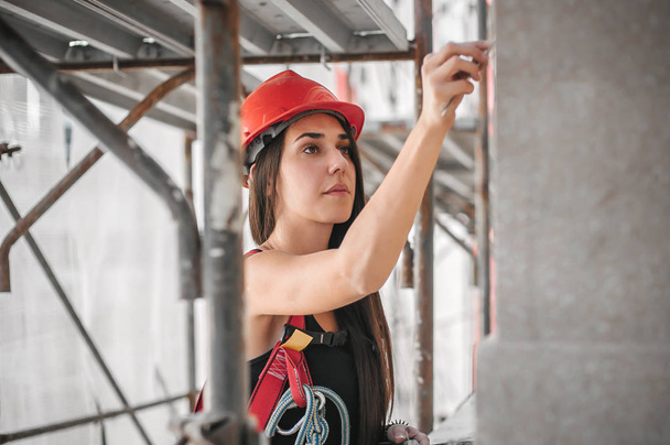 Female construction mason on the scaffolding, plastering and renovating building - 写真・画像